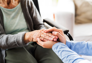 Caregiver holding the hands of a senior woman in a wheelchair