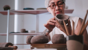 Senior woman is sculpting pottery in a studio