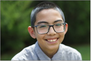 A teen boy with glasses is smiling