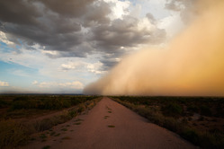 Dust in the sky and over a  rural road.