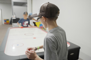 Two young boys playing air hockey 