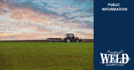 Red tractor plowing a field at sunset with birds flying overhead against a colorful sky.