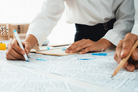 A man makes edits with a blue highlighter to a building plan