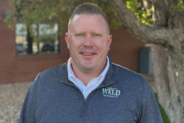 Brett Cavanaugh, Director of the Weld County Oil and Gas Energy Department, smiling in front of the Weld County Administration Building.