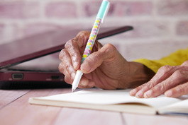 Close up of older adult writing in notebook