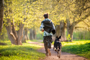 Teenage boy running in park with dog