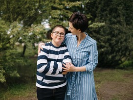 A foster mom has her arms around a young boy. 