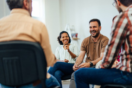 A group of adults sit in a circle and have a discussion during a support group