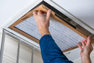 A person installing a filter in the ceiling. 