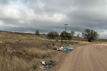 Piles of trash along a dirt road.