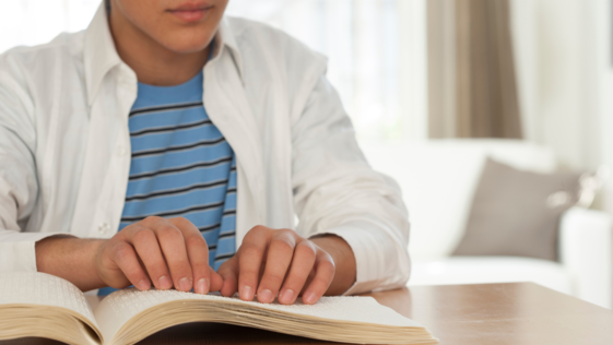 Young person reads book in braille