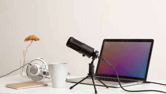 Image of a recording mic, laptop, headphones, and coffee mug