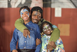 Father and two daughters with their faces painted smile at camera