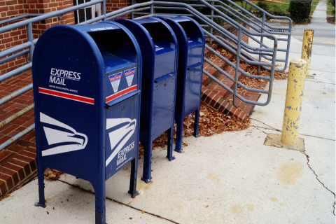 blue USPS mailboxes in front of a red brick building 