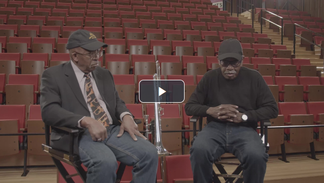 Two older men sit in director's chairs