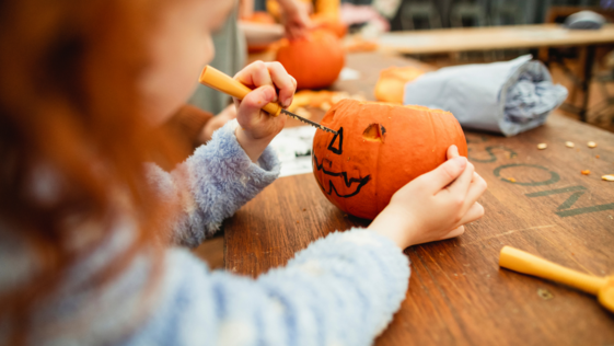 Little girl carves a pumpkin