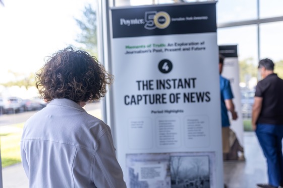 Woman looks at a Poynter Institute exhibit on news