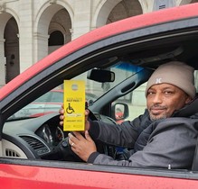 Photo of a taxi driver holding up his yellow Fast Pass