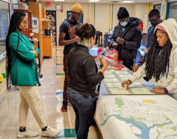 OP staff and students discuss a map and streetscape model in a classroom