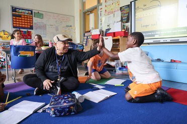 A teacher and student high five in a classroom