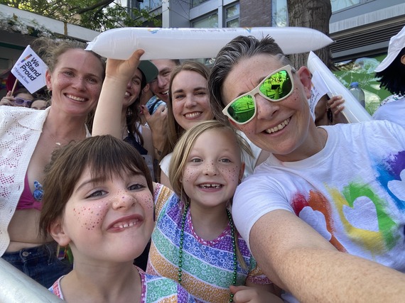 A family of people in a crowd watch the World Pride Parade.