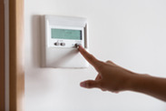 hand pressing a button on a thermostat