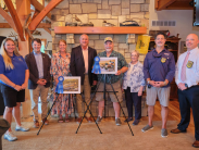 A group poses with one of the artists showing his winning waterfowl illustration.