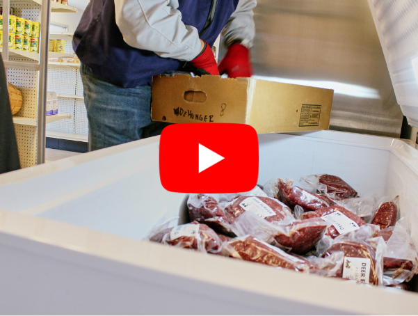 Packaged venison fills a freezer as a person in gloves loads a box of donated meat, with a YouTube play button centered over the image.