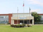 Exterior view of the Delaware City Refining Company office building with flags flying in front and a lawn surrounding the entrance.