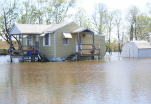 A small house sits completely surrounded by flood waters.