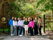 A group of ten professionals stand in front of a wrought iron gate labeled "DNREC Courtyard Visitor Entrance."