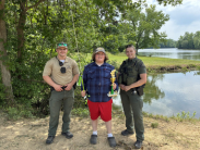 Gabriel Alfaro, winner of the 2026 Youth Fishing Tournament in Delaware, stands between a male and female DNRP officers.