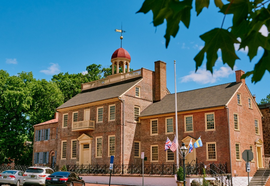 The historic brick New Castle Court House Museum is framed by a blue sky.