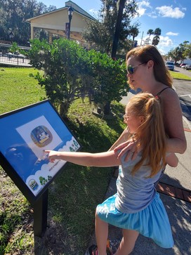 Mother and daughter read a page from the Spring Park StoryWalk