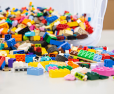 Tilted bucket with legos falling out across a table