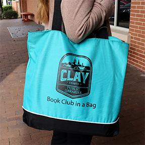 Woman holding a Clay County Public Library Book Club in a Bag kit.
