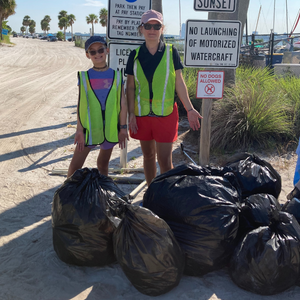 Two volunteers showing off litter collected along a beach 