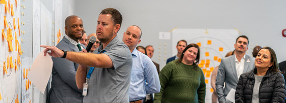 a person presenting to a group holding sticky notes