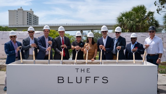 This is an image of city officials and partners wearing hard hats and holding shovels at the Bluffs groundbreaking