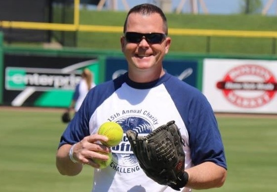 Softball player holding a ball and mitt 