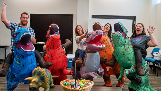 This is an image of librarians jumping and wearing dinosaur costumes for Summer Reading 2026