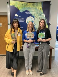 3 staff standing together holding signs