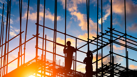 Construction workers building during a sunset