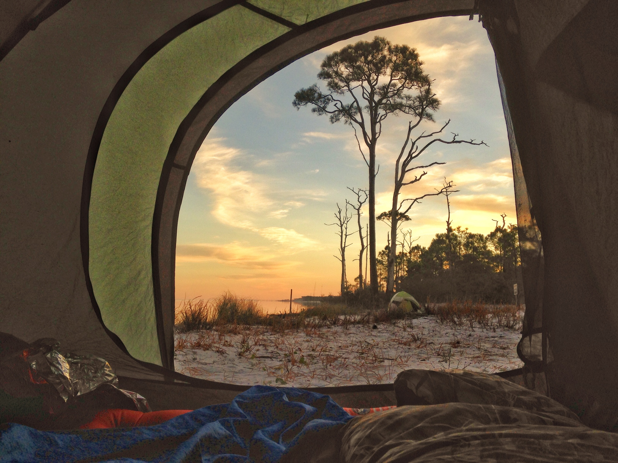 A view on a golden sunrise through a tent along the beach 
