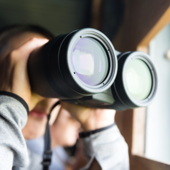 Close-up image of a woman looking through binoculars