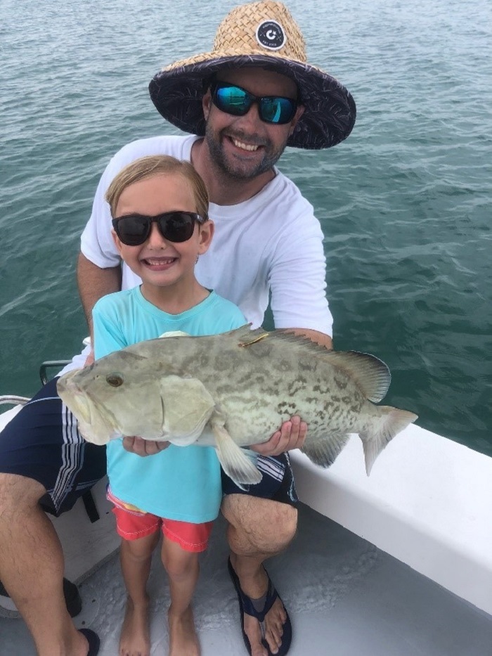 youth angler and mentor holding grouper