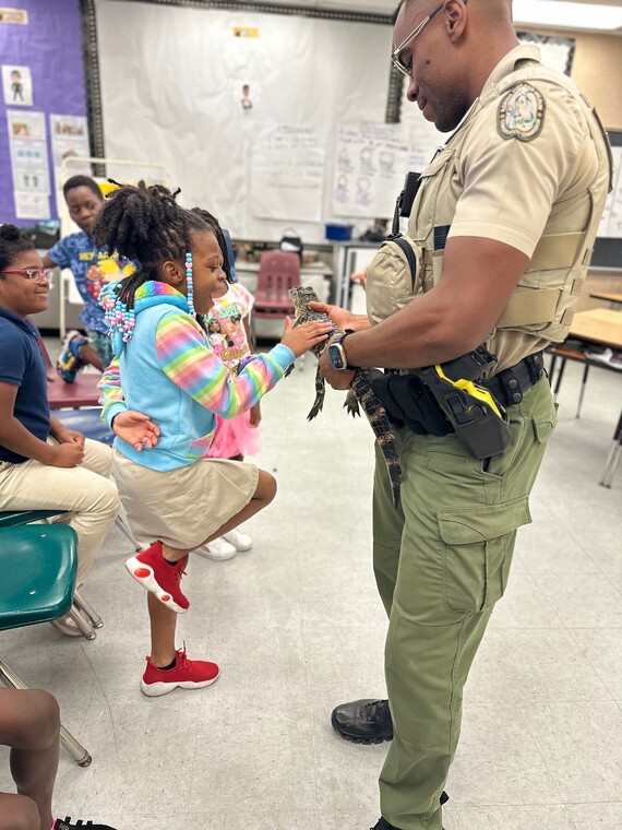 Officer showing a student a juvenile alligator