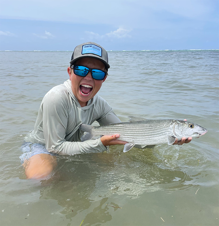 angler holding record bonefish while kneeling in water