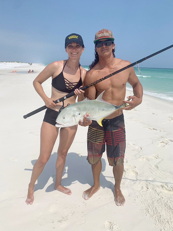 two anglers standing on beach holding a fish they just caught
