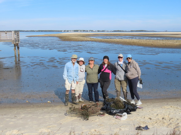 FSA partners stand by the water's edge in front of debris they collected